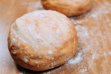 Freshly-baked bread resting on a wooden table top, with a light dusting of flour