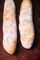 Freshly-baked bread resting on a wooden table top, with a light dusting of flour