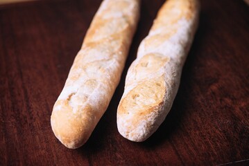 Freshly-baked bread resting on a wooden table top, with a light dusting of flour