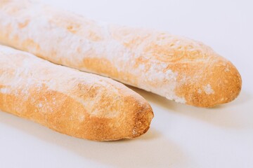 Freshly-baked bread resting on a white table top, with a light dusting of flour