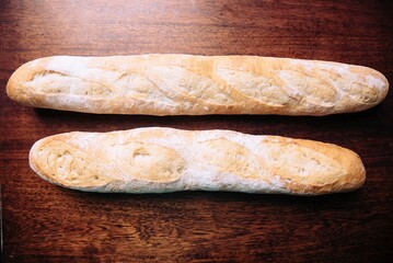 Pair of freshly-baked baguettes resting on a rustic wooden table