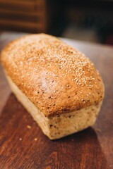 Vertical shot of a freshly-baked loaf of bread sitting atop a wooden table