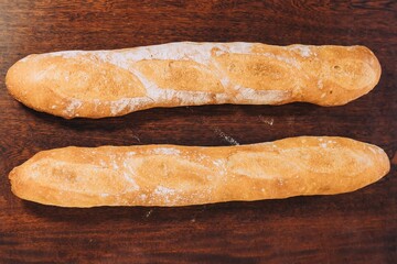 Top view of two freshly baked loaves of bread placed side by side on a wooden table