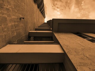 Low angle of a stone high-rise building with clouds in the background with a monochrome effect