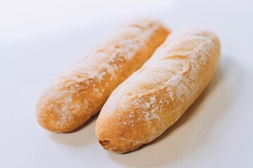 Freshly-baked bread resting on a white table top, with a light dusting of flour