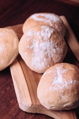 Freshly-baked bread resting on a wooden table top, with a light dusting of flour