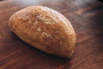 a bread sitting on a wooden table next to a knife