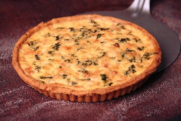 an quiche is on a brown table cloth, with forks