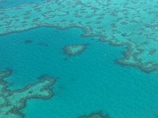 Aerial view of heart-shaped reef under the clear blue ocean water