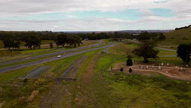 Drone time-lapse view of cars driving on highways between green fields and trees