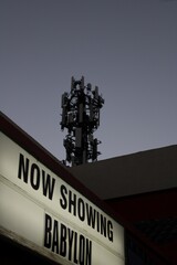 Outdoor sign for a radio tower, featuring the words "Now Showing Babylon" in bold typeface