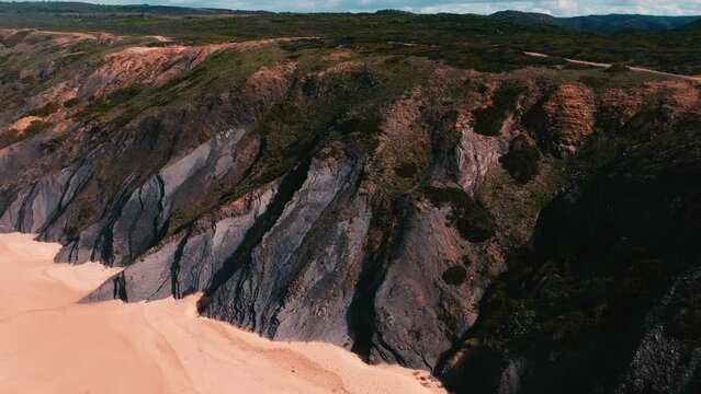 Landscape drone footage over waves splashing on cliff island range with green lawns