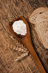 Closeup of a  freshly baked loaf of bread and a wooden spoon on a wooden table