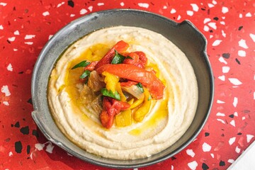 Top view of humus with vegetables on a red marble background