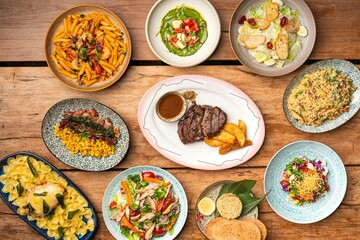 Top view of various delicious dishes served on a wooden table