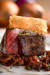 Vertical closeup of a succulent steak served with an onion ring