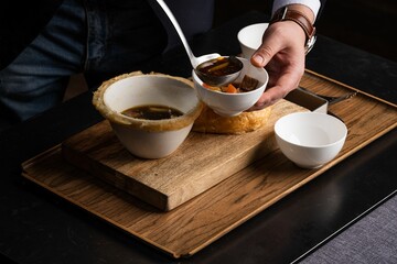 Closeup of a chef pouring a soup with carrot in a bowl