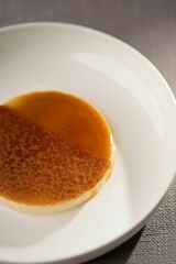 Vertical closeup of a pudding with caramel sauce on a plate