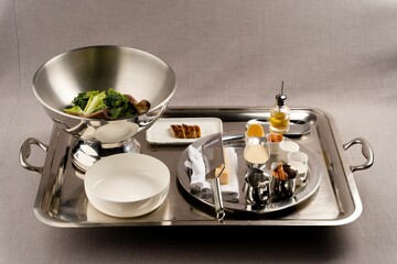 Silver tray filled with dishes of salad and steak slices with sauces