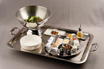 Silver tray filled with dishes of salad and steak slices with sauces