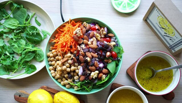 Aerial view rotating making a salad Adding spinach to dish beets quinoa seeds lemons and onions in the scene tomatoes and salad dressing