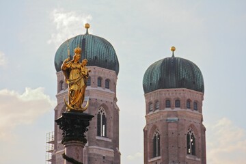 Golden statue in front of the double tower of Frauenkirche in Munich