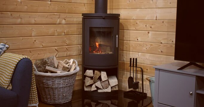 shot speeded up showing logs burning in a log fire wood burner. in a log cabin.