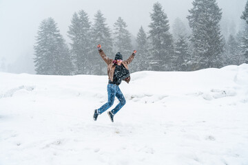 Fototapeta na wymiar Single Asian man tourist having fun, excitement, jumping, happy in middle of snow falling, View of Sonmarg Valley in Himalayas, weather was white and snowy in winter. Sonamarg, Jammu, Kashmir, India