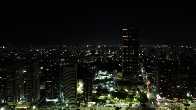 Aerial footage of the illuminated urban buildings and skyscrapers in a coastal city at night