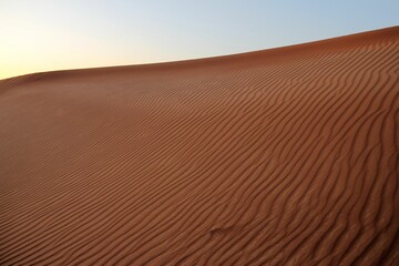 a person walking across the sand with an umbrella in hand