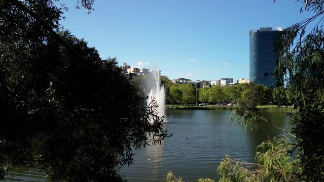 Drone footage of fountain in a lake at John Oldham Park on a sunny day in Perth, Western Australia