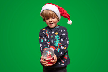 Christmas boy in a holiday clothes. Happy child on a green background with a Christmas toys. Happy...