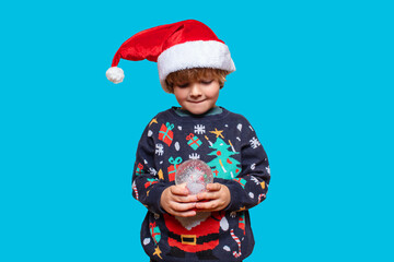 Christmas boy in a holiday clothes. Happy child on a blue background with a Christmas toys. Happy New Year. Merry Christmas!