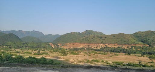 some large hills with dirt, and greenery behind them