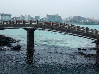 Scenic view of a bridge spanning a body of water near a city skyline: Jeju, South Korea