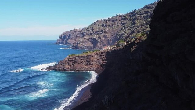 Beautiful coastline scenery blue ocean waves with green palm trees on high cliff on Tenerife on sunny day, Aerial