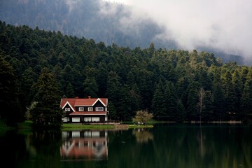 Fototapeta na wymiar Idyllic house with a red roof on the edge of a tranquil lake, providing a picturesque view