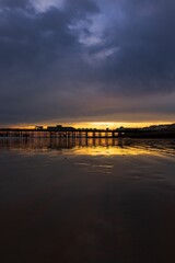 Fototapeta premium Scenic view of the sun rising over a pier jutting into a body of water