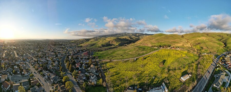 Aerial view of a landscape featuring rolling green hills, a winding road, and Milpitas neighborhood