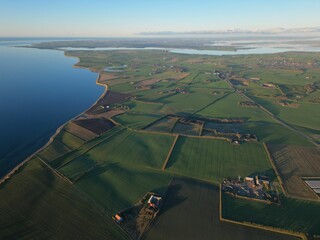 Aerial view of sectioned fields separated by tranquil waters in Thyholm, Denmark