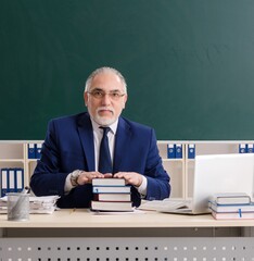 Aged male teacher in front of chalkboard