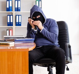 Male thief in balaclava in the office