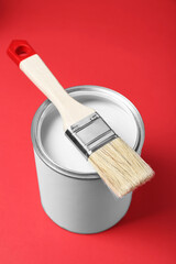 Can of white paint with brush on red background