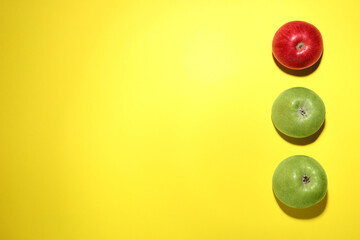 Ripe red and green apples on yellow background, flat lay. Space for text