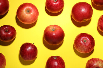 Ripe red apples on yellow background, flat lay