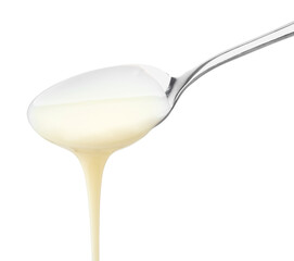 Pouring condensed milk from metal spoon isolated on white