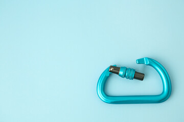 One carabiner on light blue background, top view. Space for text