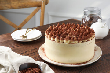 Delicious tiramisu cake with cocoa powder on wooden table