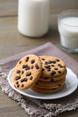 Delicious chocolate chip cookies and milk on wooden table
