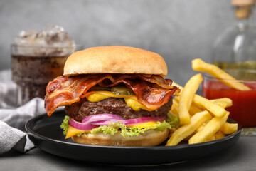 Tasty burger with bacon, vegetables and patty served with french fries on grey wooden table, closeup